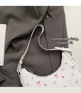 Detailed close-up of white underarm bag with pink bow floral prints and leather strap
