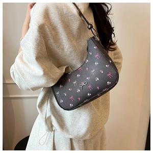 Detail of a black crescent shoulder bag with floral print and silver bow metal clasp