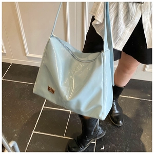 Close-up of light blue patent leather shoulder bag with gold hardware and wide strap