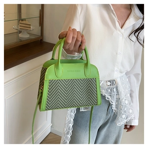 Detail of green contrast color handbag with lychee pattern and woven texture stitching