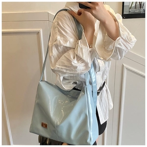 Light blue glossy leather shoulder bag with gold logo plate shown on model