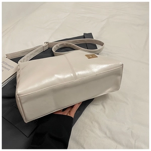 Detailed side and bottom view of beige glossy PU leather shoulder bag with gold metal logo
