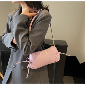 Detail of pink glossy underarm bag featuring a stylish bow tie knot on the side strap