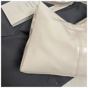Close-up of beige PU leather tote bag showing detailed side stitching and soft texture