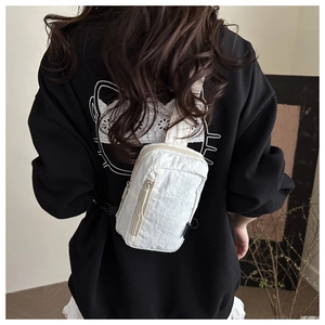 White nylon mini crossbody bag shown on model's back highlighting size and sporty style