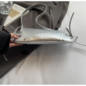 Detail of silver metallic leather underarm bag featuring side knots and metal rivet accents