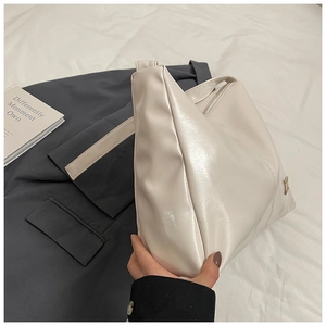 Close-up of minimalist white oversized crossbody bag in glossy faux leather material