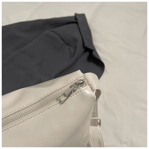 Macro detail of creamy white shoulder bag featuring smooth leather and silver metal zipper
