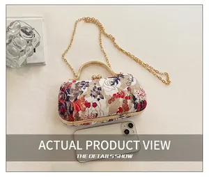 Detail of floral embroidery evening clutch with gold metal handle and chain strap