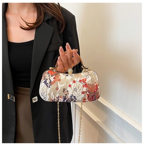 Detail of floral embroidery bag with pearl clasp and golden handle on black suit