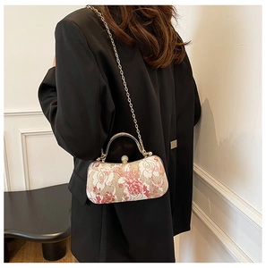 Detail of floral embroidery evening bag with pearl clasp and golden chain strap
