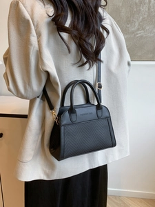 Borsa tote nera minimalista con trama intrecciata e finiture dorate su sfondo bianco