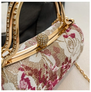 Detail of floral embroidery evening bag with rhinestone clasp and gold metal handles