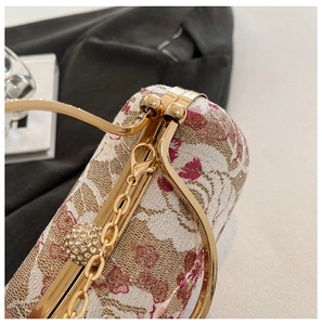 Detailed close-up of floral embroidery on handbag with gold ring handle and rhinestone charm