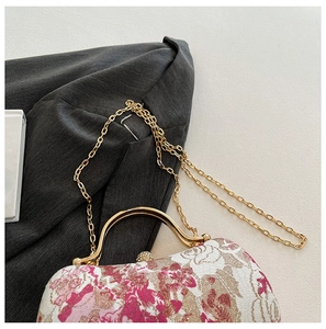Detail of floral embroidery texture and gold metal handle on a pink evening clutch bag