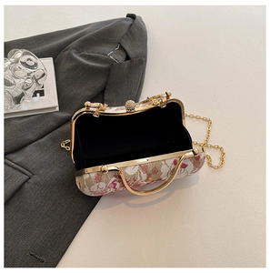 Detail of floral embroidery on ivory clutch bag with golden chain and diamond clasp