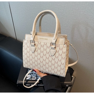 Detail of elegant beige tote bag with M-pattern print and refined metal logo hardware