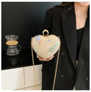 Detailed close-up of heart-shaped glitter bag with gold chain and feather pattern