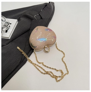 Detail of heart-shaped clutch bag with sparkling sequins and champagne gold metallic chain