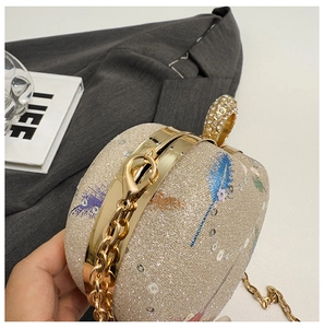 Macro view of sparkly gold evening bag with feather embroidery and rhinestone ring handle