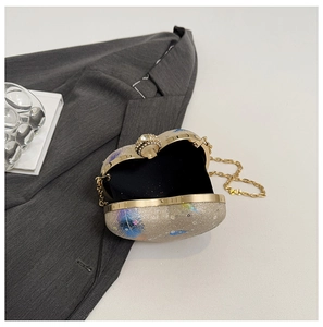Detail of evening clutch featuring purple feather print, gold frame and ring clasp