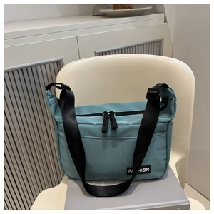 Detail of lake blue nylon bag featuring adjustable wide strap and fashion textile label