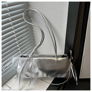 Detail view of silver metallic shoulder bag with delicate white lace bow decoration