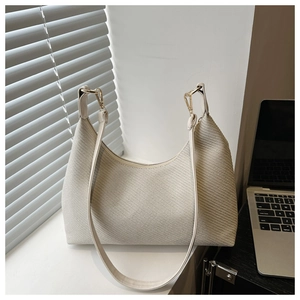 Close-up of beige woven texture and gold metal hardware on half-moon shoulder bag