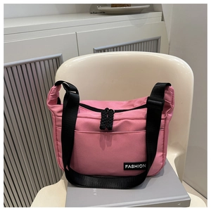 Detail view of pink nylon crossbody bag with dual black zippers and adjustable wide strap