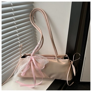Detail of pink shoulder bag featuring delicate white lace trim and multiple silk ribbon bows