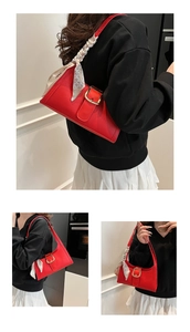 Détail du sac rouge à motif croco avec boucle dorée et décoration en foulard de soie