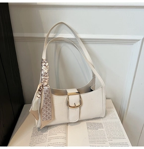 Détail du sac sous le bras blanc à texture crocodile avec foulard décoratif sur magazine