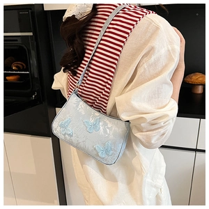 Detail of light blue hobo bag with delicate 3D butterfly embroidery and floral texture