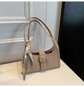 Détail du sac baguette beige à motif crocodile avec boucle dorée et foulard en soie