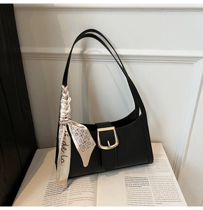 Détail du sac hobo noir avec boucle dorée et foulard en soie à motif géométrique