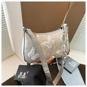 Detailed view of 3D lace butterfly embroidery on a white pearlescent tote bag