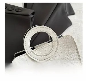 Detail of white crocodile pattern tote with minimalist circular cutout top handle
