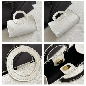 Detail of white crocodile pattern PU leather handbag with unique circular handle and magnetic closure