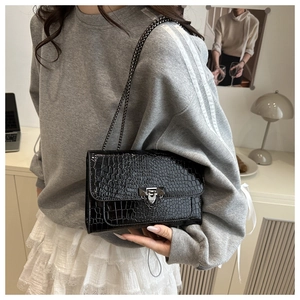 Détail du sac noir texture crocodile avec boucle argentée et bandoulière chaîne métal