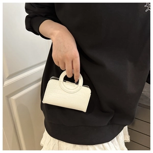 Close-up of a white croc-embossed mini handbag with unique circular handles for women