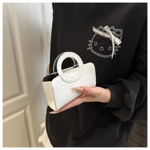 Mini white handbag with crocodile pattern and round handle held by hand