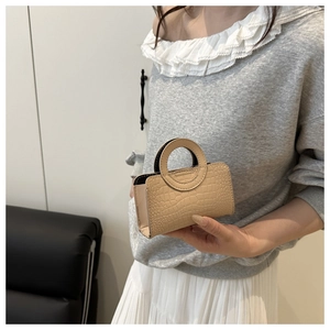 Detail of cream PU tote with crocodile texture and circular cut-out handles