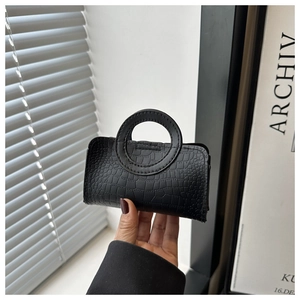 Detail of black mini PU tote bag with crocodile texture and unique circular handle