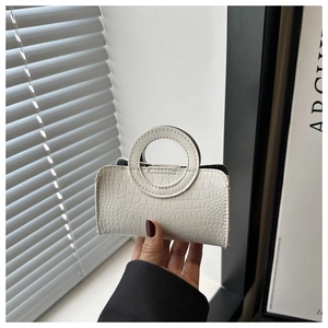 Close-up of white crocodile pattern handbag with a unique circular handle detail