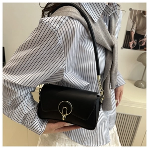 Detail of black leather shoulder bag with gold round buckle and metallic chain strap