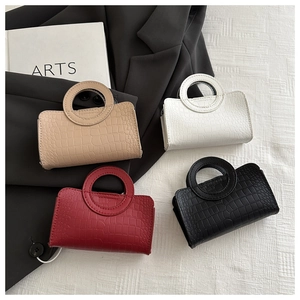 Flat lay of four crocodile-patterned handbags with round cut-out handles in various colors