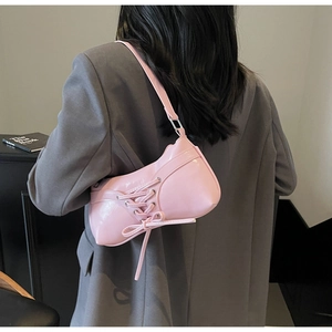 Detail of pink patent leather underarm bag featuring aesthetic corset-style lacing decoration