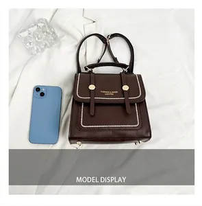 Detail view of small brown leather bag with golden twist lock next to a blue phone
