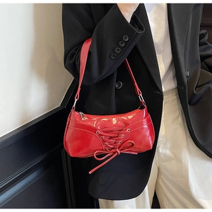 Detail of red patent leather shoulder bag with decorative bow and silver hardware