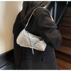 Detail of silver metallic underarm bag with lace-up bow design on female model